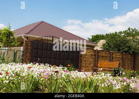 Belle maison clôturée et avec beau jardin fleuri sur un front. Banque D'Images