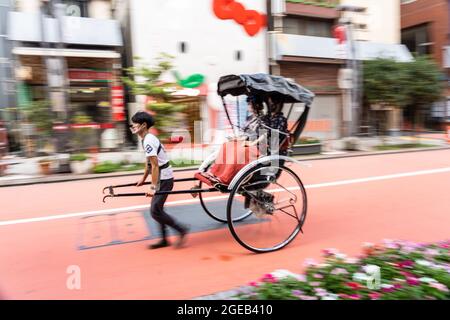 Un pousse-pousse ou un jinrikisha transporte les touristes autour du temple bouddhiste Sensoji et du quartier historique d'Asakusa à Tokyo, au Japon. Banque D'Images