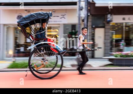 Un pousse-pousse ou un jinrikisha transporte les touristes autour du temple bouddhiste Sensoji et du quartier historique d'Asakusa à Tokyo, au Japon. Banque D'Images