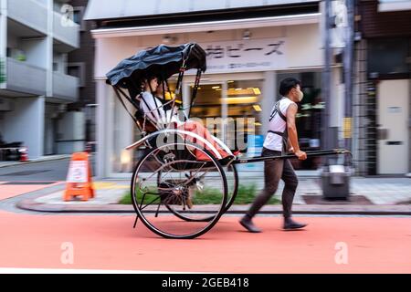 Un pousse-pousse ou un jinrikisha transporte les touristes autour du temple bouddhiste Sensoji et du quartier historique d'Asakusa à Tokyo, au Japon. Banque D'Images