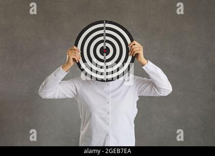 Femme qui cache son visage derrière une cible de tir comme un concept de fixer un objectif d'affaires Banque D'Images