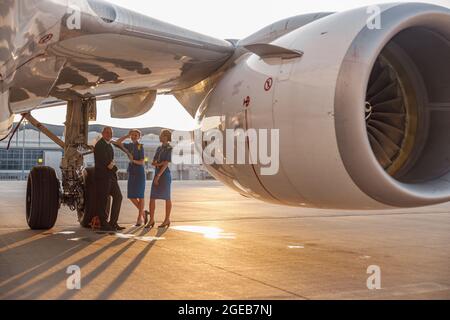 Heureux pilote et deux jolies hôtesses debout ensemble, assis sur un avion et souriant à la caméra après l'atterrissage ou avant le départ Banque D'Images