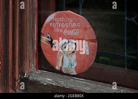 Publicité de style Retreo Coca-Cola dans une fenêtre usée et abîmée. Banque D'Images