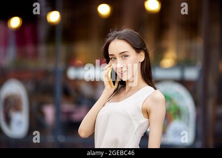 Une femme fine et heureuse parle en extérieur avec un smartphone. Banque D'Images