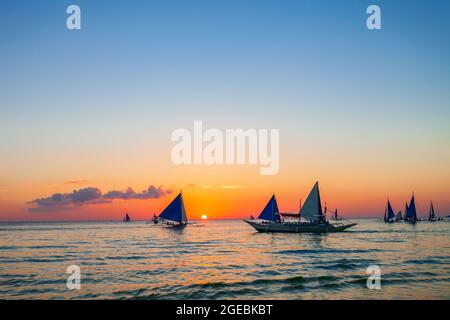 Bateau philippin traditionnel à l'idyllique plage de sable blanc de l'île Boracay à Philiberines au coucher du soleil Banque D'Images