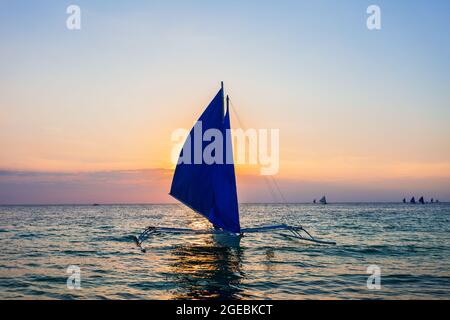 Bateau philippin traditionnel à l'idyllique plage de sable blanc de l'île Boracay à Philiberines au coucher du soleil Banque D'Images