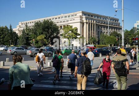 Bucarest, Roumanie - 17 août 2021 : les gens traversent la rue près du Palais Victoria qui abrite le siège du gouvernement roumain, à Bucarest Banque D'Images