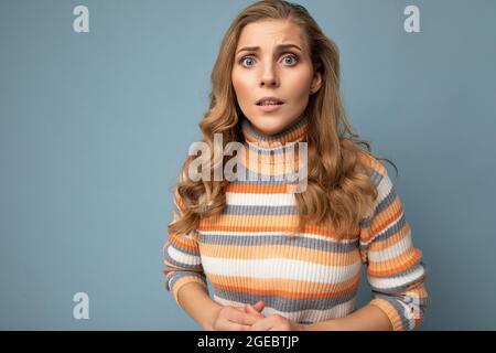 Photo portrait de jeune attrayante beau triste bouleversé nerveux blonde femme avec des émotions sincères portant le pull rayé isolé sur fond bleu Banque D'Images