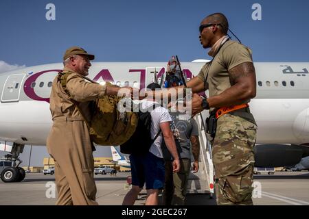 Base aérienne d'Al Udeid, Qatar. 18 août 2021. Un membre du 8e Escadron de mobilité aérienne expéditionnaire aide le personnel de l'ambassade des États-Unis d'Afghanistan à bord d'un vol de Qatar Airways vers le Koweït dans le cadre de l'opération alliés refuge, le 17 août 2021, à la base aérienne d'Al Udeid, au Qatar. Photo de l'homme d'aviation principal Noah Coger/États-Unis Force aérienne/UPI crédit: UPI/Alay Live News Banque D'Images