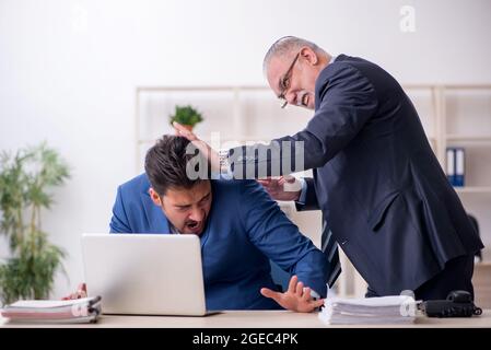 Vieux patron et jeune employé dans le concept d'intimidation Banque D'Images