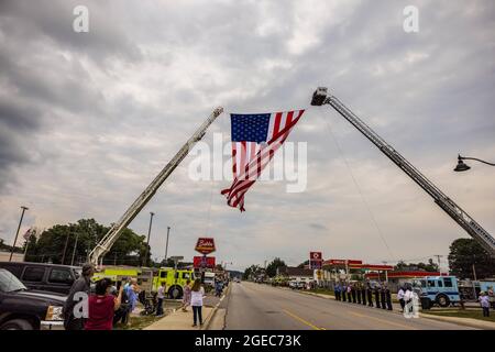 Bloomington, États-Unis. 18 août 2021. Un drapeau américain survole W. Morgan Street lors d'un cortège funéraire pour le ambulancier décédé Brandon Staley à Spencer, Indiana. Staley est mort d'une crise cardiaque alors qu'il travaillait comme ambulancier pour le service EMS du comté d'Owen (Emergency Medical Services). Staley venait de répondre à un accident de véhicule et était dans une ambulance avec des survivants de l'accident les aidant sur le chemin d'un hôpital quand il lui-même est tombé malade. (Photo de Jeremy Hogan/SOPA Images/Sipa USA) crédit: SIPA USA/Alay Live News Banque D'Images