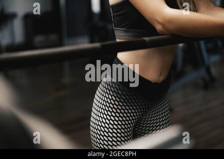 Gros plan d'une femme qui s'est penchée sur la barbell dans la salle de gym tout en faisant de l'exercice Banque D'Images