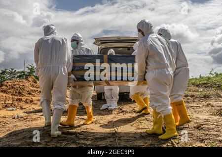 Kendari, Indonésie. 18 août 2021. (NOTE DE LA RÉDACTION : l'image dépeint la mort) les professionnels de la santé vêtus de costumes de protection portent un cercueil d'une victime Covid-19 pour inhumation. Le processus funéraire pour les patients Covid-19 ayant des protocoles de santé est effectué par des agents de santé hospitaliers à Kendari. Bien que le nombre de patients traités par COVID-19 diminue, le taux de mortalité est constant chaque jour. Crédit : SOPA Images Limited/Alamy Live News Banque D'Images