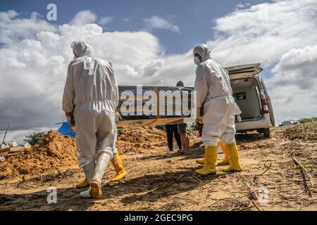 Kendari, Indonésie. 18 août 2021. (NOTE DE LA RÉDACTION : l'image dépeint la mort) les professionnels de la santé vêtus de costumes de protection portent un cercueil d'une victime Covid-19 pour inhumation. Le processus funéraire pour les patients Covid-19 ayant des protocoles de santé est effectué par des agents de santé hospitaliers à Kendari. Bien que le nombre de patients traités par COVID-19 diminue, le taux de mortalité est constant chaque jour. Crédit : SOPA Images Limited/Alamy Live News Banque D'Images