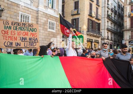 Barcelone, Catalogne, Espagne. 18 août 2021. Le protesté est vu avec un drapeau afghan à côté des manifestants derrière un drapeau afghan et un signe qui dit que les extrémistes ont démontré ce qu'ils craignent le plus : Une fille avec un livre.près de cinq cents personnes ont manifesté à Barcelone en solidarité avec les filles et les femmes d'Afghanistan et en défense de leurs droits sous le slogan ''Afghanistan: Pour une vie avec dignité et liberté' (Credit image: © Thiago Prudencio/DAX via ZUMA Press Wire) Banque D'Images