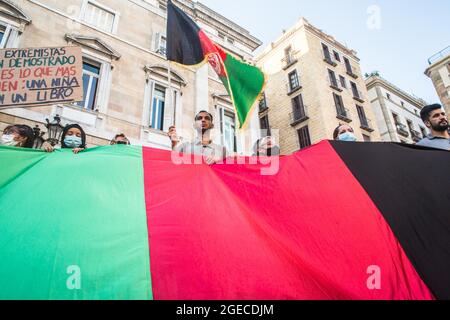 Barcelone, Catalogne, Espagne. 18 août 2021. Un drapeau afghan est visible à côté des manifestants derrière un drapeau afghan.près de cinq cents personnes ont manifesté à Barcelone en solidarité avec les filles et les femmes d'Afghanistan et en défense de leurs droits sous le slogan ''Afghanistan: Pour une vie avec dignité et liberté' (Credit image: © Thiago Prudencio/DAX via ZUMA Press Wire) Banque D'Images