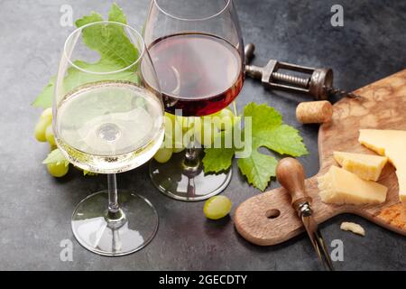 Verres à vin blanc et rouge, planche à raisins et hors-d'œuvre avec fromage Banque D'Images