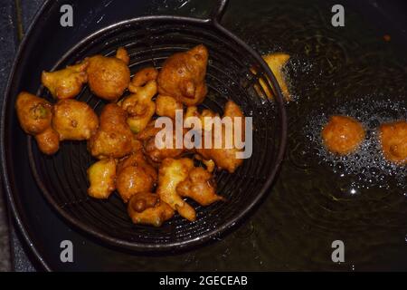 beignets de farine de gramme, huile bouillante dans une poêle à frire à fond sombre Banque D'Images