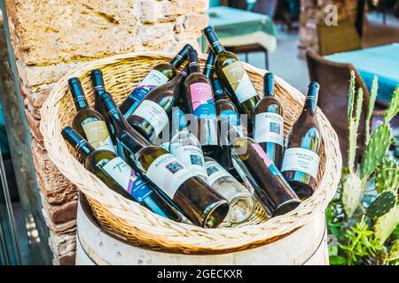 Antalya, Turquie - 12 août 2021 : bouteilles de vin dans un panier sur la véranda d'été d'un café ou d'un restaurant en plein air. Photo de haute qualité Banque D'Images