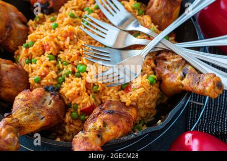 Pilons de poulet rôtis au riz djuvec serbe servis dans une casserole en fonte sur fond de table sombre Banque D'Images