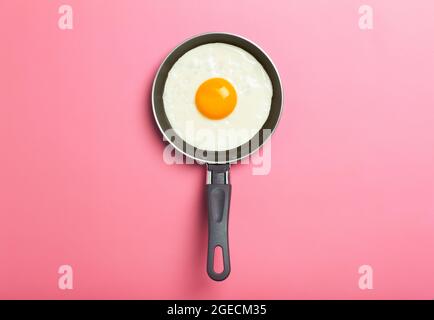 L'œuf frit est minime. Œuf frit dans une poêle sur fond rose vide. Petit déjeuner créatif et idée de nourriture. Copier l'espace Banque D'Images