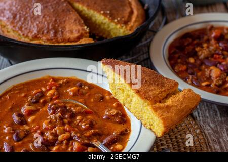 Soupe épicée aux haricots avec pain de maïs frais et fait maison sur fond rustique et en bois de table Banque D'Images