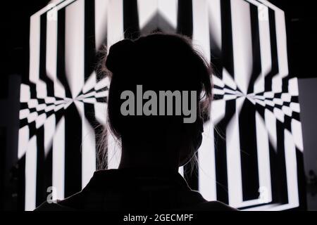 Femme regardant le grand écran de cube avec l'illusion d'optique hypnotique tournant Banque D'Images