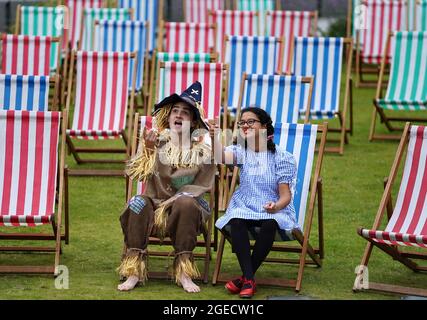 Aditi Jehangir en tant que Dorothy et Ewan Shand en tant que Scarecrow représentant le magicien d'Oz un des films populaires alignés pour le Festival du film de cette année dans la ville s'assoient sur des chaises longues dans une zone d'observation extérieure de la place St Andrew, dans le cadre du Festival international du film d'Édimbourg. Date de la photo: Jeudi 19 août 2021. Banque D'Images