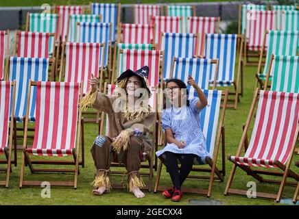 Aditi Jehangir en tant que Dorothy et Ewan Shand en tant que Scarecrow représentant le magicien d'Oz un des films populaires alignés pour le Festival du film de cette année dans la ville s'assoient sur des chaises longues dans une zone d'observation extérieure de la place St Andrew, dans le cadre du Festival international du film d'Édimbourg. Date de la photo: Jeudi 19 août 2021. Banque D'Images