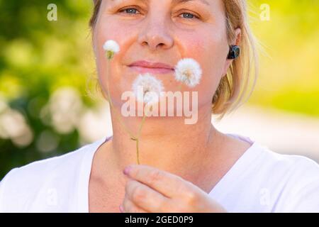 Gros plan d'une femme blonde sportive adulte portant un casque et tenant dans les mains la lance pissenlit. Banque D'Images