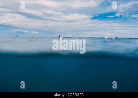 04 avril 2021. Bali, Indonésie. Les surfeurs qui attendent se brandir dans l'océan bleu Banque D'Images