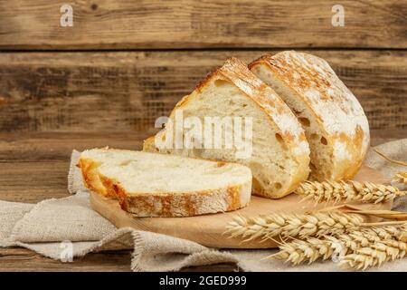 Pain fraîchement cuit aux oreilles de blé, morceaux parfumés sur une planche à découper. Table en bois d'époque, produits de boulangerie prêts à l'emploi, espace de copie Banque D'Images