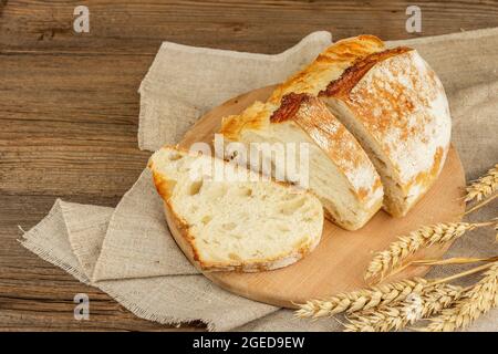 Pain fraîchement cuit aux oreilles de blé, morceaux parfumés sur une planche à découper. Table en bois d'époque, plats cuisinés, vue du dessus Banque D'Images