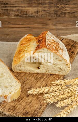 Pain fraîchement cuit aux oreilles de blé, morceaux parfumés sur une planche à découper. Table en bois d'époque, produits de boulangerie prêts à l'emploi, espace de copie Banque D'Images