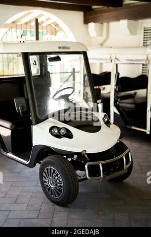 Une voiturette de golf à six places se trouve dans un parking couvert sur un carreau Banque D'Images