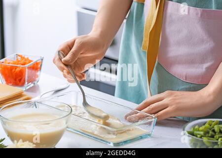 Femme préparant de délicieux lasagnes de légumes à table dans la cuisine, en gros plan Banque D'Images