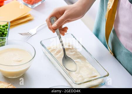 Femme préparant de délicieux lasagnes de légumes à table dans la cuisine, en gros plan Banque D'Images