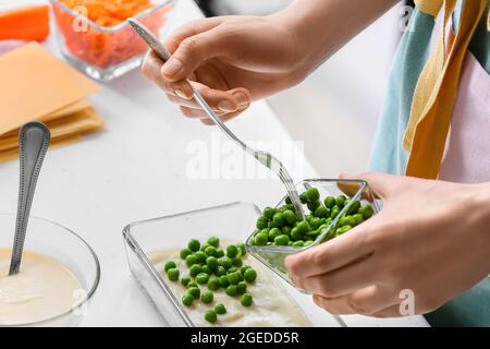 Femme préparant de délicieux lasagnes de légumes à table dans la cuisine, en gros plan Banque D'Images