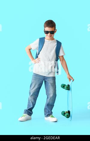 Petit écolier avec skateboard sur fond de couleur Banque D'Images