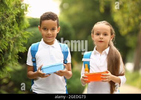 Jolis petits enfants avec des boîtes à lunch à l'école à l'extérieur Banque D'Images