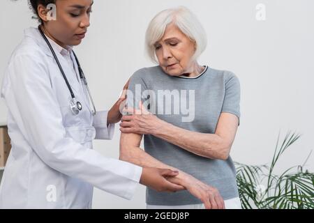 Un médecin afro-américain touche un bras de patient sénior malade Banque D'Images