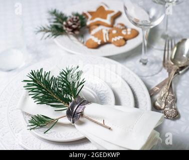 Table de Noël avec assiettes texturées blanches, couverts vintage et biscuits de noël traditionnels Banque D'Images