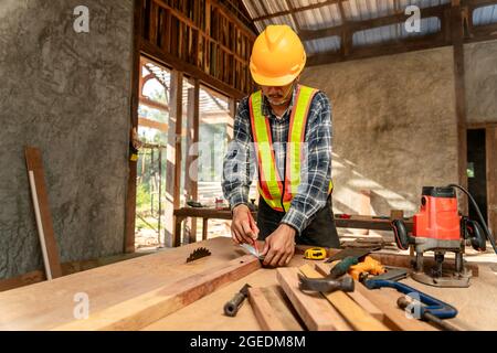 Un charpentier travaillant sur des machines à travailler le bois dans un atelier de menuiserie. Carpenter travaille sur le chantier de construction Banque D'Images