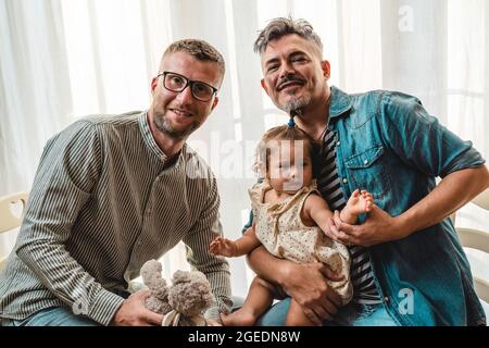 Portrait de la famille heureux LGBTQ à la maison - couple gay et leur fille - concept de diversité et relation de famille LGBTQ Banque D'Images