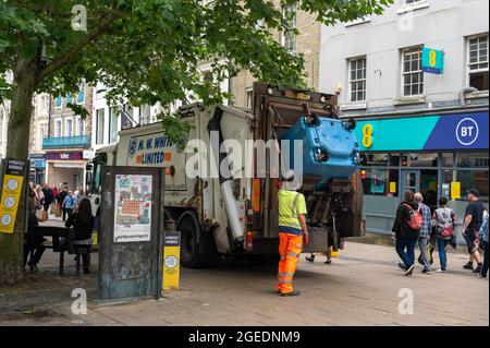 Un aspirateur vidant une poubelle commerciale bleue dans le centre de Norwich lors d'une journée chargée Banque D'Images