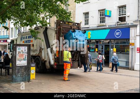 Un aspirateur vidant une poubelle commerciale bleue dans le centre de Norwich lors d'une journée chargée Banque D'Images