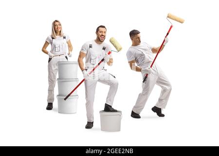 Groupe de peintres de maison joyeux dansant et jouant avec des rouleaux de peinture isolés sur fond blanc Banque D'Images