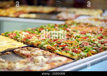Morceaux carrés de pizza exposés sur le comptoir de la petite pizzeria italienne dans la ville de Bergame, Italie. Banque D'Images