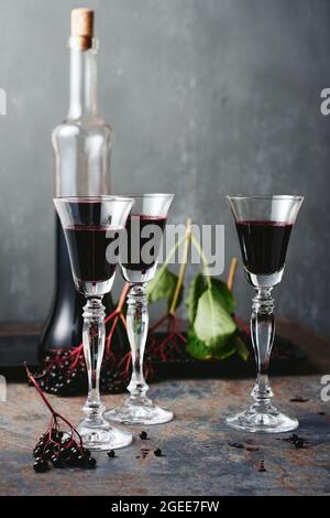 Liqueur de sureau maison en verres et une bouteille, baies de sureau mûres. Banque D'Images