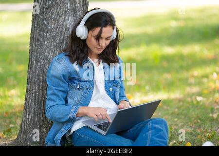 Photo rognée d'une femme de 40 ans avec ordinateur portable dans le parc de la ville pendant un appel vido en ligne. Concept de travail en ligne ou concept d'un enseignement en ligne distant Banque D'Images